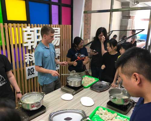 People cooking and interacting around a table with dumplings