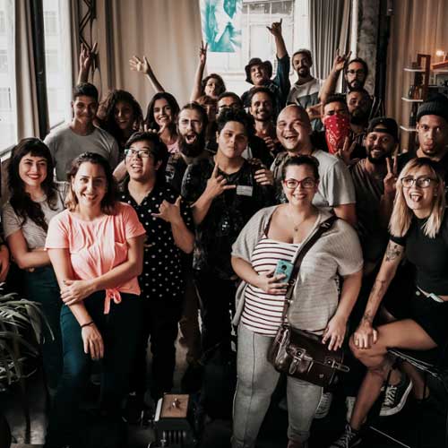 A diverse group of people smiling and posing together in a warmly lit indoor space