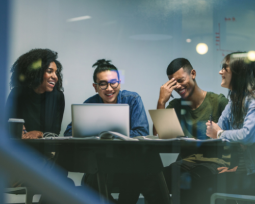 Four students working in a classroom on laptops