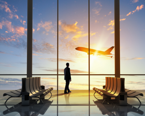 A person at the airport with a plan traveling in the background
